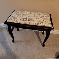 Side angle view of the bench showing curved legs and floral cushioned seat