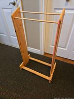 Wooden blanket rack showing side and front view, with three horizontal dowels and solid side panels in natural wood finish.