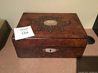 Front view of antique wooden box showing keyhole and brass trim.