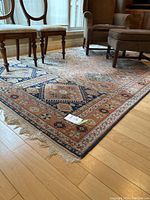 Full view of area rug under chairs showing overall design, colors, fringe and condition
