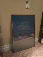 Front view of the framed beach print showing sandy beach, waves, and sky with clouds.