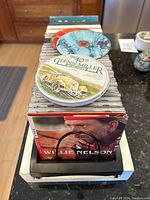 Top view showing a stack of assorted CDs stored in a black plastic holder including visible Glenn Miller Orchestra and Willie Nelson CDs