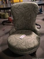 Front angled view of the Victorian slipper chair showing the light green floral upholstery and wooden legs with casters