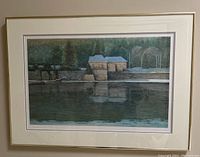 Framed landscape painting with water, trees, and house, showing overall art piece with gold-tone frame.
