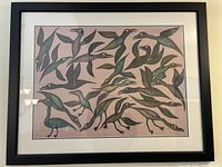 Full view of framed lithograph on wall, showing black frame, white mat, and multiple flying ravens on pale pink background.