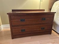 Front view of the wooden night stand showing two drawers with dark metal handles and the rectangular shape.
