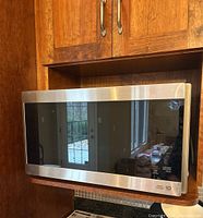 Front view of LG stainless steel microwave mounted in kitchen cabinet.