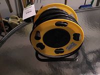 Photo of yellow outdoor extension cord reel showing the cord wound around it and metal handle.