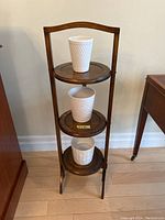 Wooden 3-tier plant stand with three white ceramic pots placed on each tier, showing overall appearance and structure.