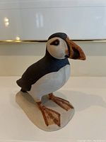 Side view of the puffin figurine showing detailed paint and shape on a ceramic base.
