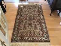 Full view of the floral patterned wool rug showing overall condition and design.