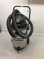 Full view of Shop-Vac QSP Contractor 6.5 HP vacuum with hose wrapped around top and mounted on wheeled base.