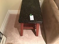 View from above showing the full side table, reddish wood frame, mission style legs and the granite top in place.