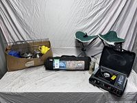 Full shot of camping lot with chairs, tents, kettles, cups, small stove and tent untested