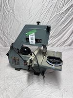 Full side profile of the gray and black Delta 10 bandsaw showing the blade on the right and black wired components on the left.