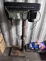 Full view of Delta drill press showing base, column, and head with motor and lever handle.