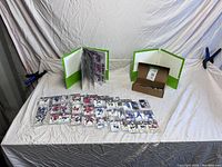 Two green binders open with visible hockey cards in plastic sleeves and hockey cards laid in front on surface.