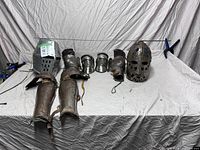 Full view of the lot showing armour pieces and fencing weapon on a draped surface.
