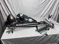 Full lot display with armor pieces, fencing swords, and shield on table with fabric background.