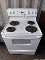 Front view of white Moffat stove with four coil burners and control knobs on front panel, showing some dirt and signs of use.