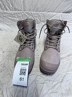 Front view of a pair of Palladium waterproof women's boots with laces tied, tags attached, placed on a light fabric background.