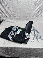 Black punching bag labeled RAD GIANT with included hanging chain hardware on a beige surface.