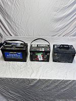 Lot image showing three batteries side by side on a white sheet background.