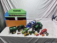 Full view of toy vehicles on white backdrop showing tractors, trailer, loader, cement mixer truck, and multiple small vehicles.