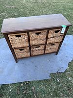 Full view of the solid wood TV stand showing six woven basket drawers arranged two over three.