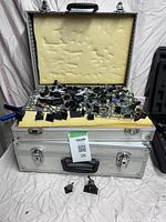 Aluminum case open with yellow foam insert holding loose unassembled miniature parts and bases