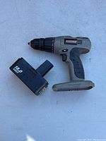 Photo showing Craftsman cordless drill body and removable 18V battery pack lying next to it on a flat surface.