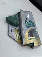 Green 3-outlet power block and power cord partially visible inside original packaging.