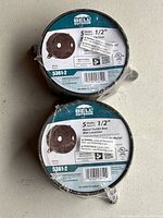 Two round Bell Outdoor metal outlet boxes, sealed and stacked, showing front labels with specifications.