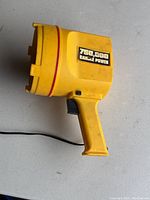 Side view of handheld yellow spotlight showing power rating label 750,000 Candle Power