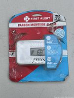 Front view of packaged First Alert carbon monoxide alarm in original red and blue packaging with digital display showing CO level.