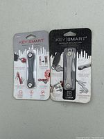 Two KeySmart compact key holders in original packaging, one aluminum and one titanium model