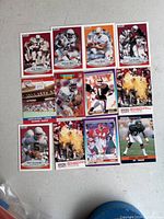 Photo showing 12 NFL Pro Set football cards laid out on a white surface with player names visible on cards.