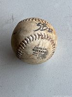 Softball baseball with 'SB12' marking and official text visible, showing used condition.