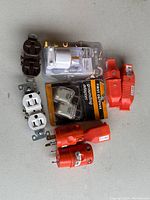 Overall view of electrical duplex receptacles, grounding adapters, plugs and safety devices on gray surface