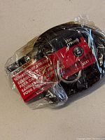 Two coiled black rubber tarp straps sealed in plastic packaging, labeled with measurements and pack quantity