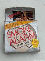 Front view of the smoke alarm box showing branding, model, and battery included note.