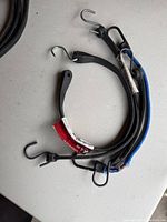 Coiled black rubber straps with metal S hooks attached on each end, displaying the Stallion branding tags.