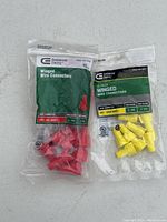 Two sealed bags of Commercial Electric winged wire connectors; one with red connectors, one with yellow connectors.