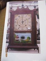 Full front view of clock on pegboard background showing entire mahogany veneer case, dial and glass panel