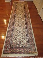 Full length view of the antique South Asian runner rug showing overall pattern, shape, and color on hardwood floor.