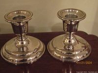 Pair of silver-tone candleholders with wide round bases.
