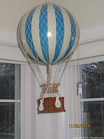 Full view of large decorative hot air balloon with basket hanging inside a room corner