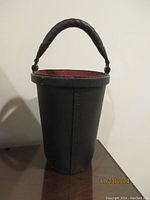 Handmade leather fire bucket with black exterior and red interior, with rounded leather handle