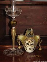 Murano glass candle stick holder and Venetian jester mask displayed on wooden surface