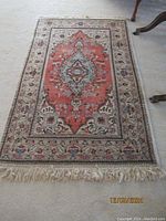 Full view of the oriental hand knotted rug laid flat on carpeted floor showing overall design, shape and size.